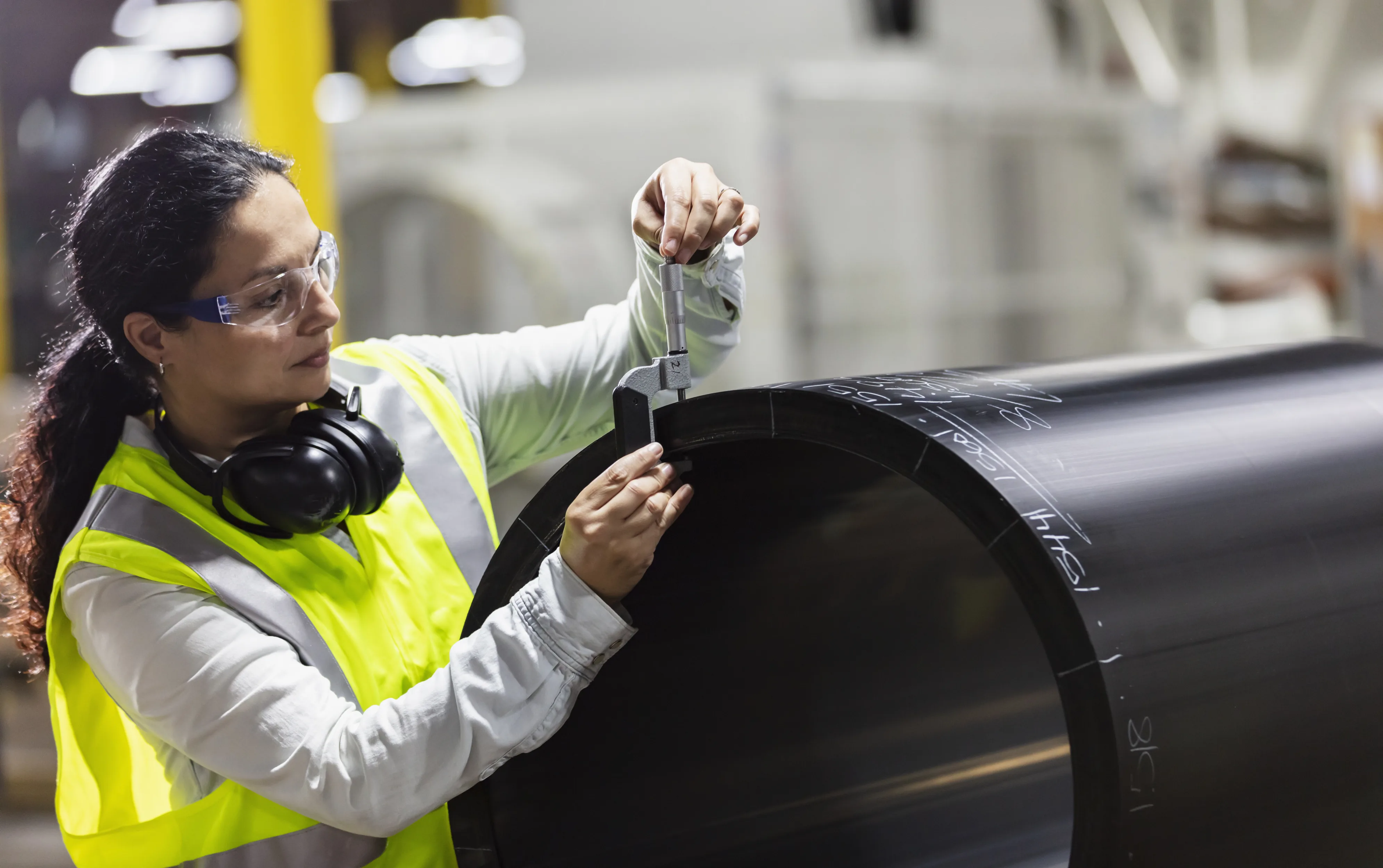 Technician measuring a large steel cylinder bore — dimensional verification at the KEZAD workshop